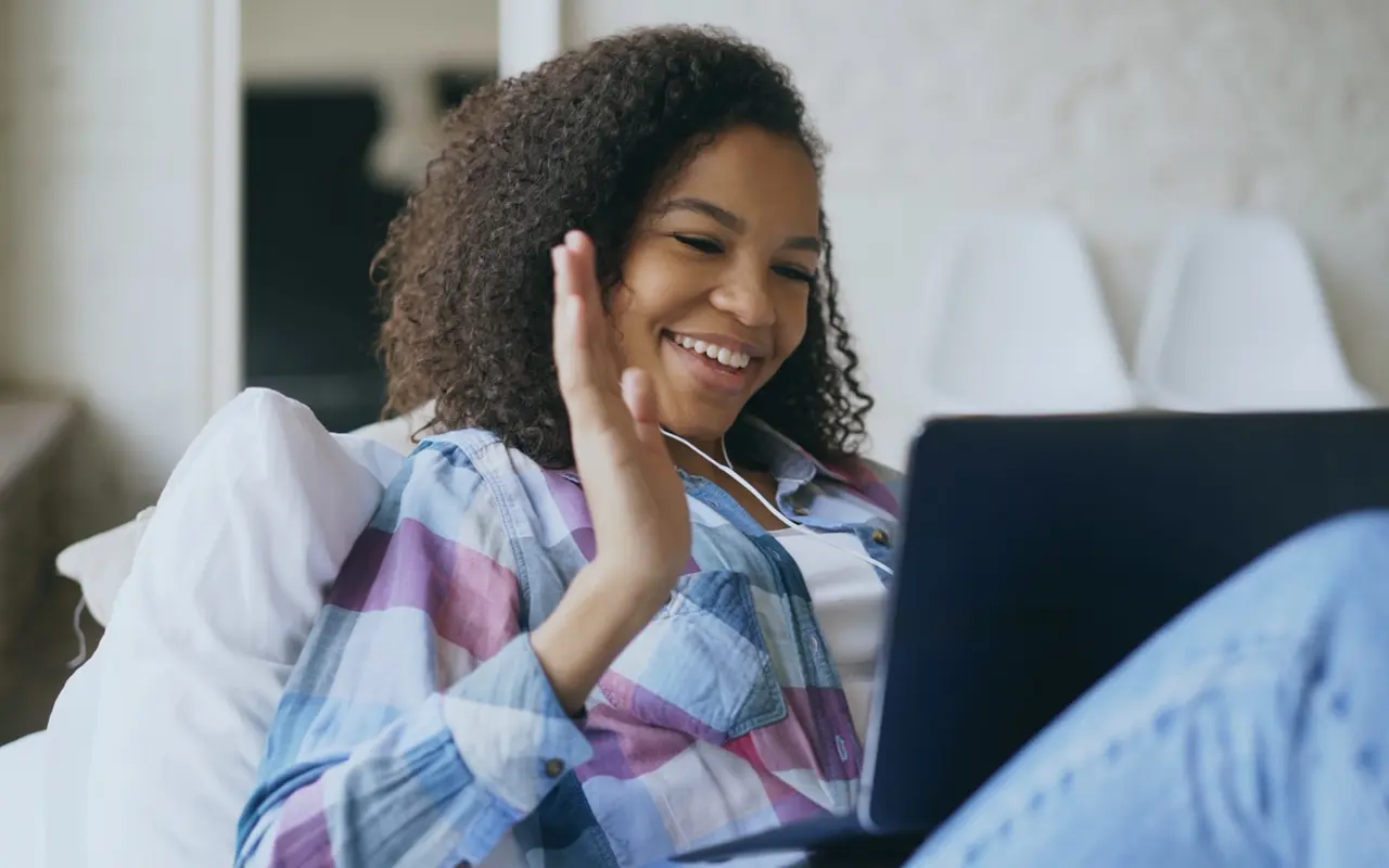 A student relaxing on a couch while messaging on her laptop